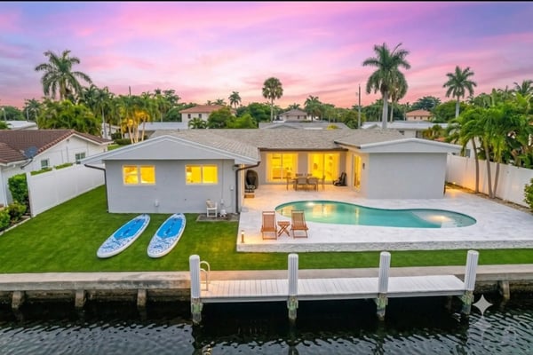Modern backyard with swimming pool, lounge chairs, and stone house with large windows
